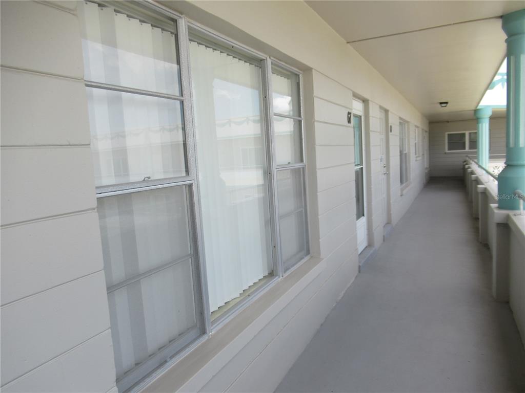An exterior walkway with light-colored walls, windows, and doors leads along a building — 2371 ISRAELI DRIVE UNIT 67, CLEARWATER, FL