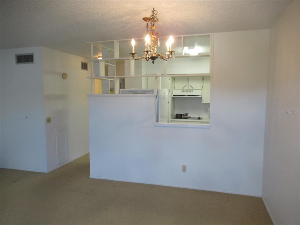 A dining area features a chandelier, carpeted floors, and a partial wall opening to a kitchen — 2371 ISRAELI DRIVE UNIT 67, CLEARWATER, FL