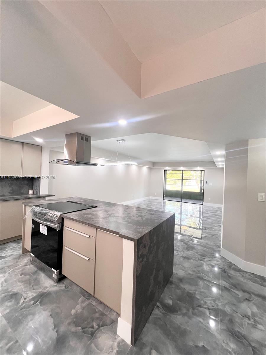 A modern kitchen with a stone-topped island and stainless steel range overlooks an open living area — 4930 E Sabal Palm Blvd # 206, Tamarac FL 33319, TAMARAC, FL