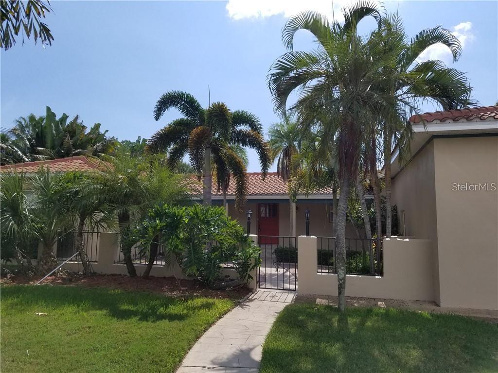 A walkway leads to a gated courtyard entrance of a house with palm trees — 4000 BELLE VISTA DRIVE, ST PETERSBURG, FL