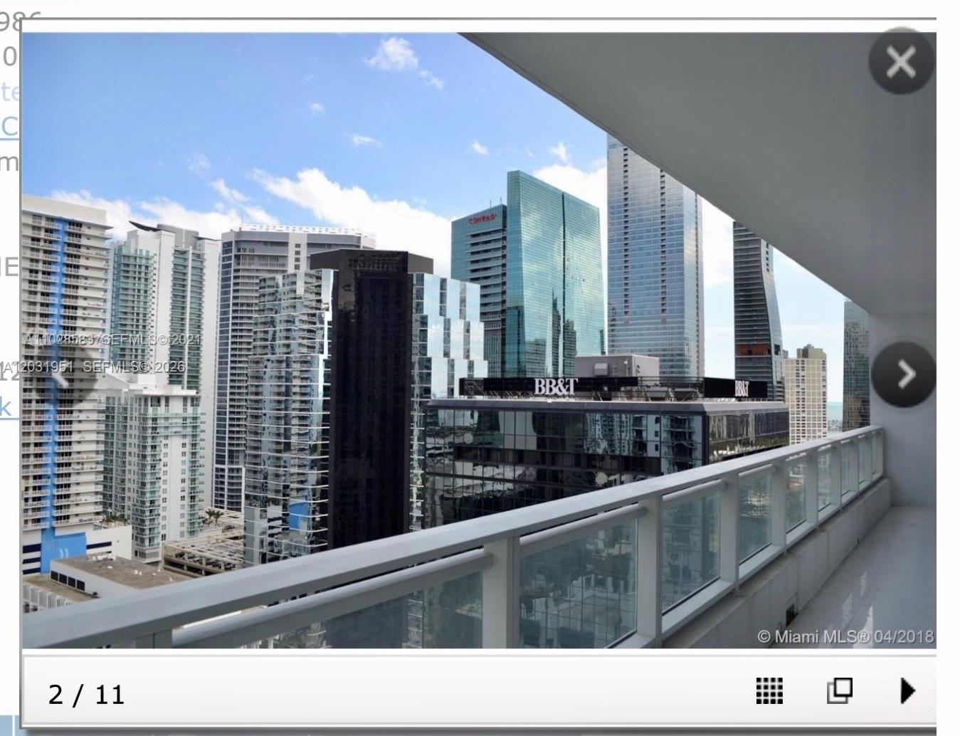A balcony view overlooking a dense city skyline with multiple high-rise glass skyscrapers — MIAMI, FL