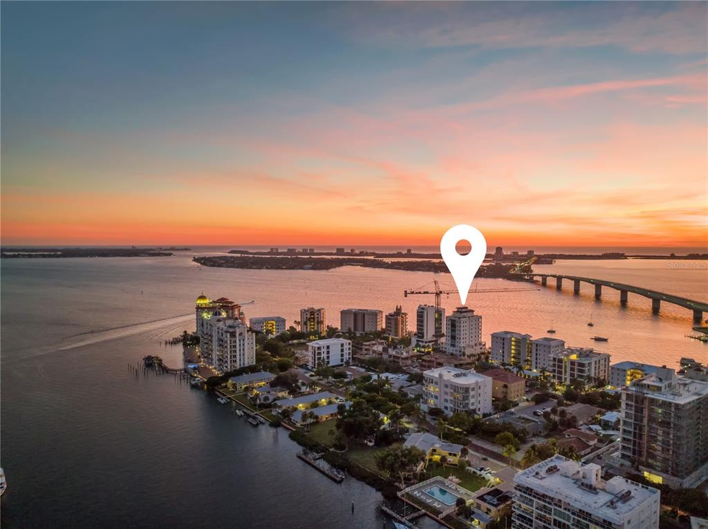 An aerial view shows a coastal city skyline with a bridge at sunset — 258 GOLDEN GATE POINT UNIT 701, SARASOTA, FL