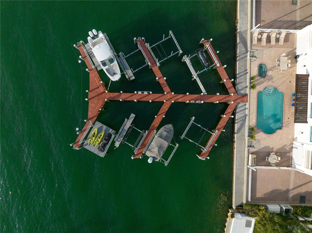 An aerial view shows a wooden boat dock with multiple slips extending into green water — 258 GOLDEN GATE POINT UNIT 701, SARASOTA, FL