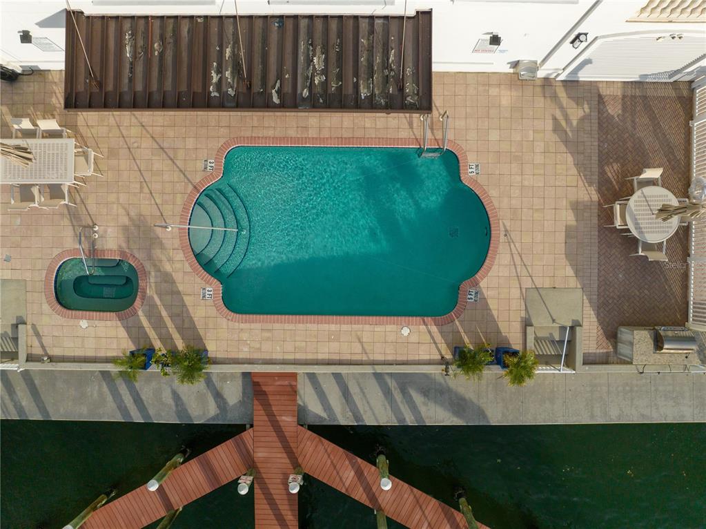 An aerial view shows a swimming pool, hot tub, and wooden dock by the water — 258 GOLDEN GATE POINT UNIT 701, SARASOTA, FL