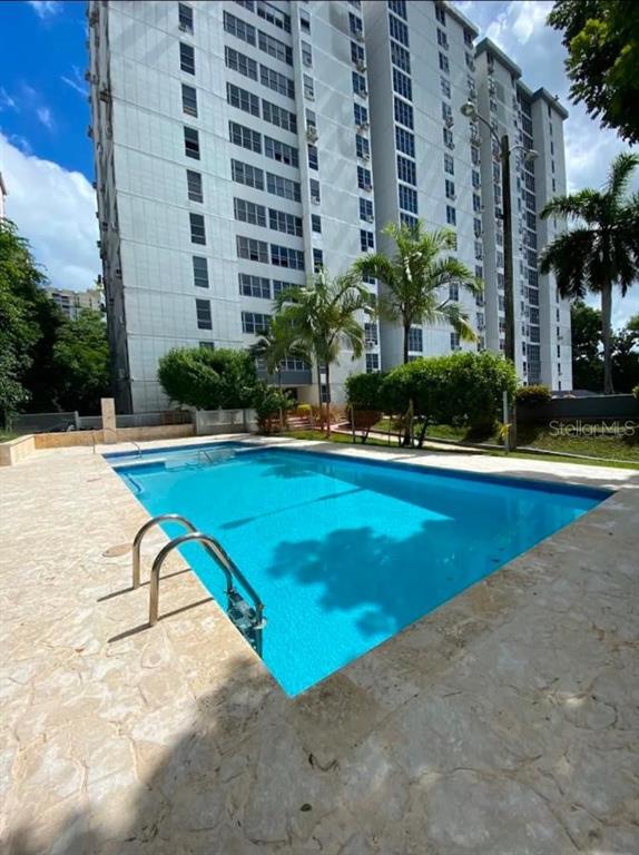 A rectangular swimming pool with a metal ladder sits on a stone patio beside a building — 1785 COND MILLENIA PARK UNIT 14, SAN JUAN, PR