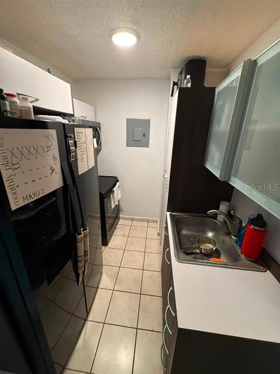 A narrow kitchen features a black refrigerator, a stainless steel sink, and light-colored floor tiles — 1785 COND MILLENIA PARK UNIT 14, SAN JUAN, PR