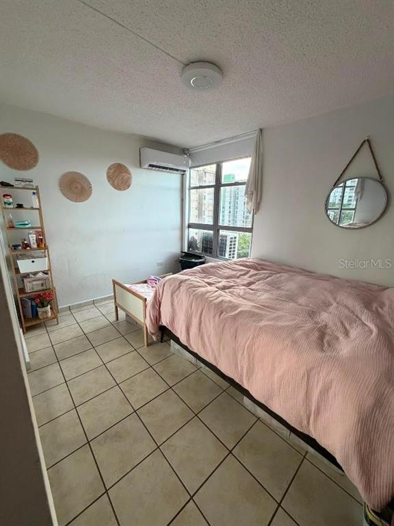 A bedroom with a bed, a tall shelving unit, a round mirror, and tile flooring — 1785 COND MILLENIA PARK UNIT 14, SAN JUAN, PR