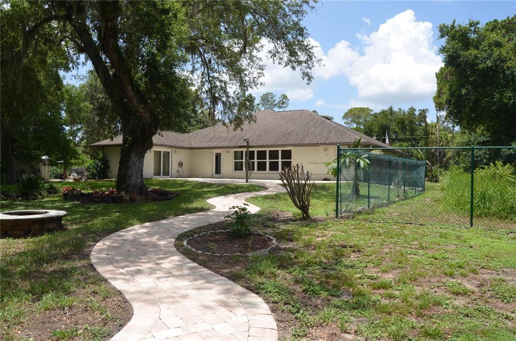 A paved walkway leads to the back of a house with a large oak tree — 4450 JODY AVENUE, NORTH PORT, FL
