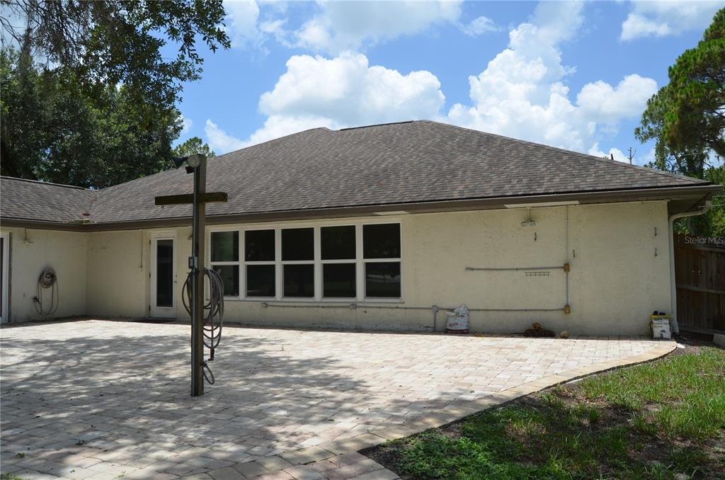 A paved patio sits outside the rear of a house with a light-colored stucco exterior — 4450 JODY AVENUE, NORTH PORT, FL