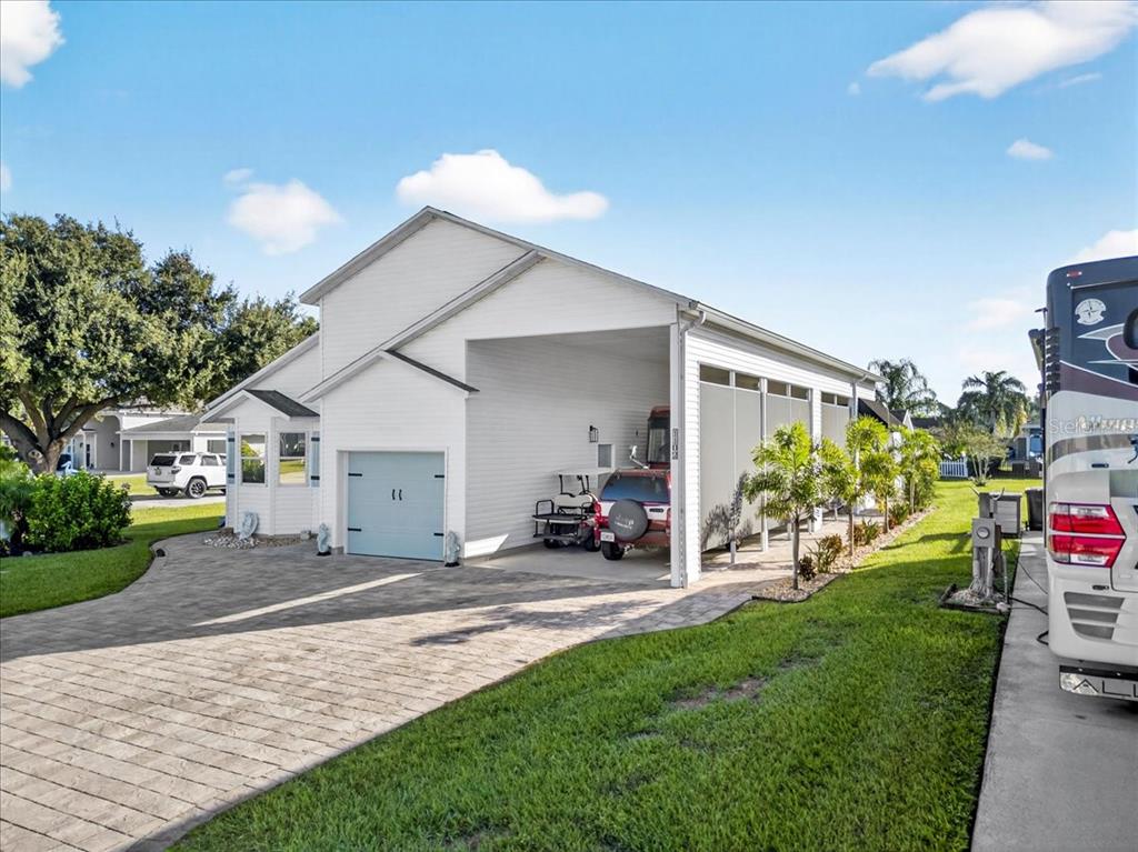A white house with a paved driveway, a small garage, and a large open carport — 1102 MOTORCOACH DRIVE, POLK CITY, FL