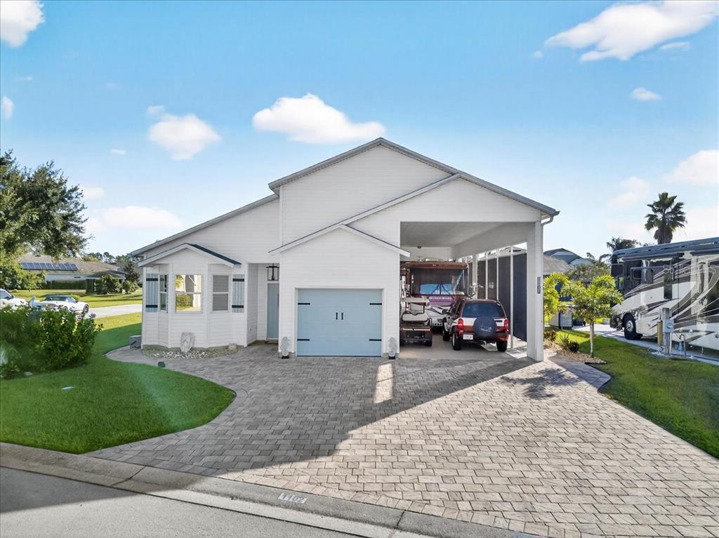 A white house with a paved driveway, a garage, and an attached RV carport — 1102 MOTORCOACH DRIVE, POLK CITY, FL