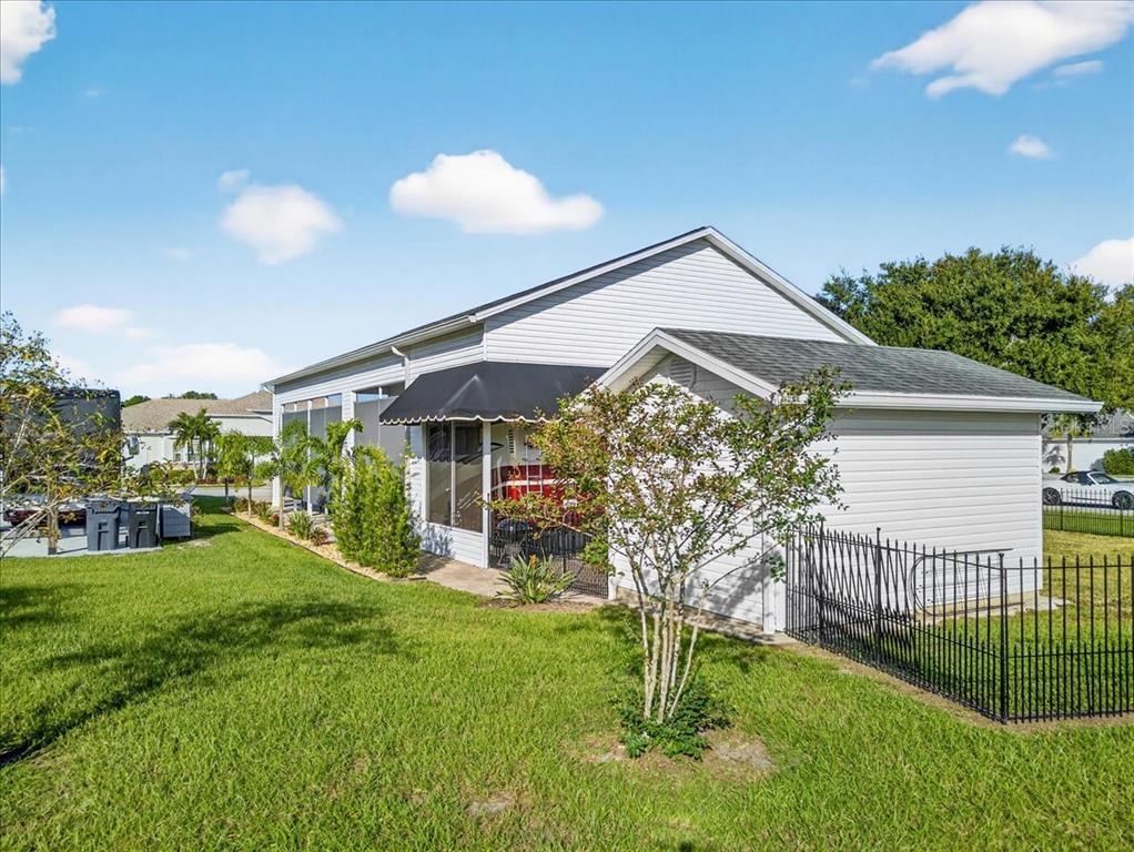 A side view of a house with light-colored siding, a black awning, and a fenced yard — 1102 MOTORCOACH DRIVE, POLK CITY, FL