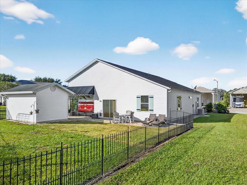 The exterior of a white house features a patio, a detached shed, and a fence — 1102 MOTORCOACH DRIVE, POLK CITY, FL