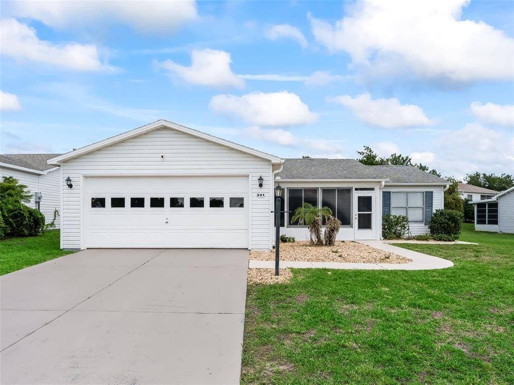 A single-story house with white siding, a two-car garage, and a screened-in front porch — 321 SAN MARINO DRIVE, THE VILLAGES, FL