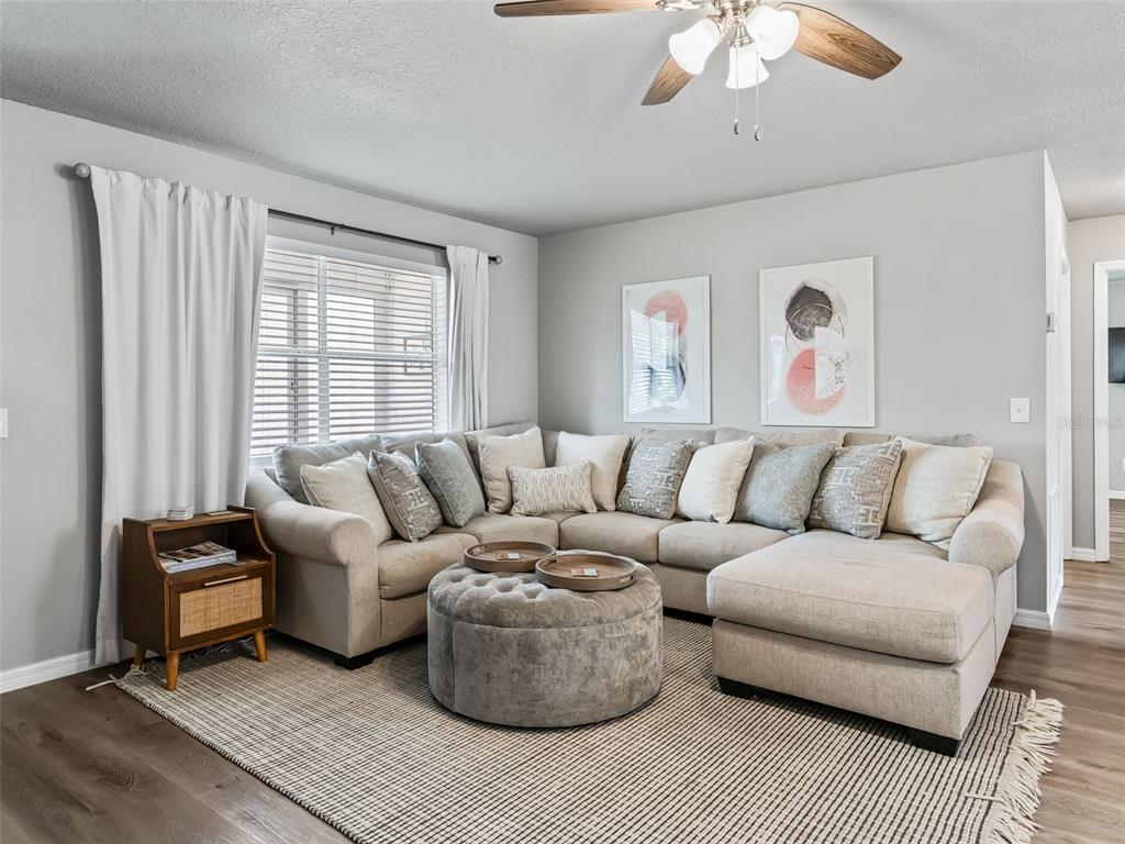 A living room features a large sectional sofa, a round ottoman, and a patterned rug — 321 SAN MARINO DRIVE, THE VILLAGES, FL
