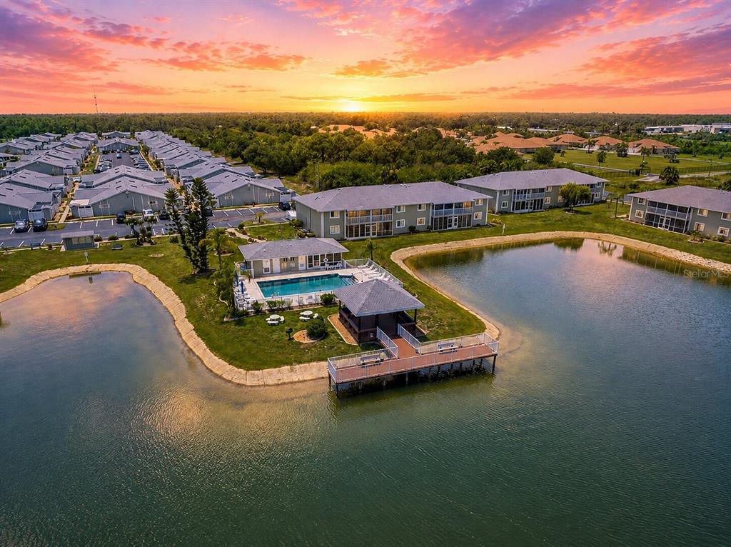 An aerial view shows a community pool, a gazebo, and a dock beside a lake — 3310 LOVELAND BOULEVARD UNIT 506, PUNTA GORDA, FL