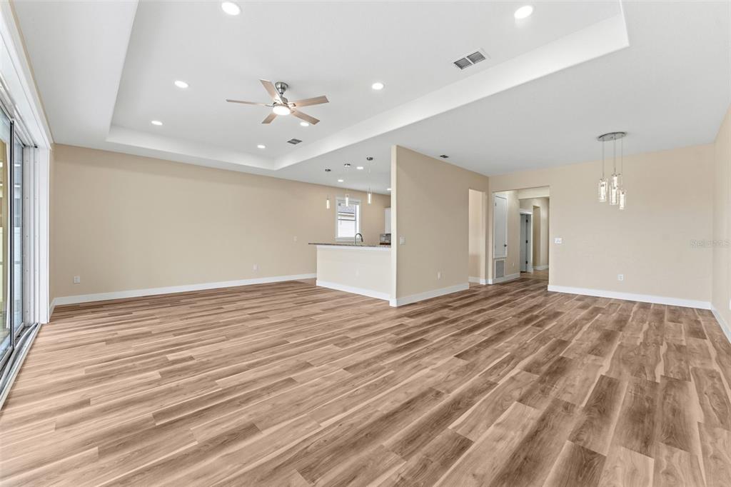 An open-concept living area features light wood-look flooring, a tray ceiling, and a kitchen island — 11514 ASHTON FIELD AVENUE, RIVERVIEW, FL