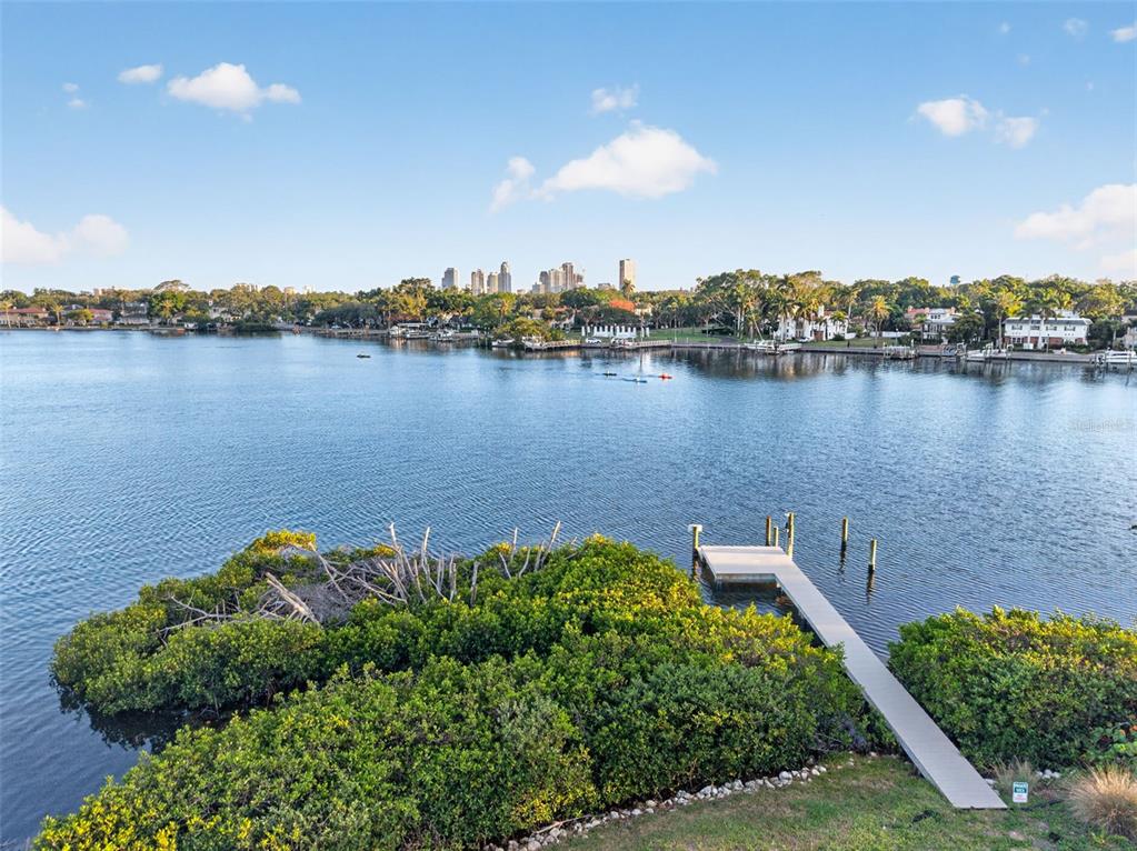 A wooden dock extends into a calm bay with a city skyline in the distance — 1026 MONTEREY BOULEVARD NE, ST PETERSBURG, FL
