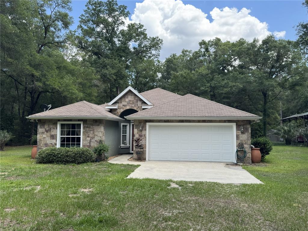 A single-story house with a stone facade, a two-car garage, and a shingled roof — 13350 SW 61ST PLACE ROAD, OCALA, FL