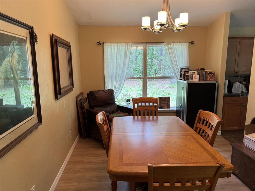 A dining room features a wooden table, four chairs, a leather armchair, and a window — 13350 SW 61ST PLACE ROAD, OCALA, FL