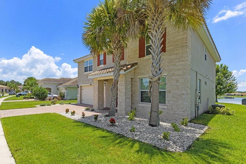 A two-story house with stone veneer siding, palm trees, and a gravel front yard — 3802 CARRICK BEND DRIVE, KISSIMMEE, FL