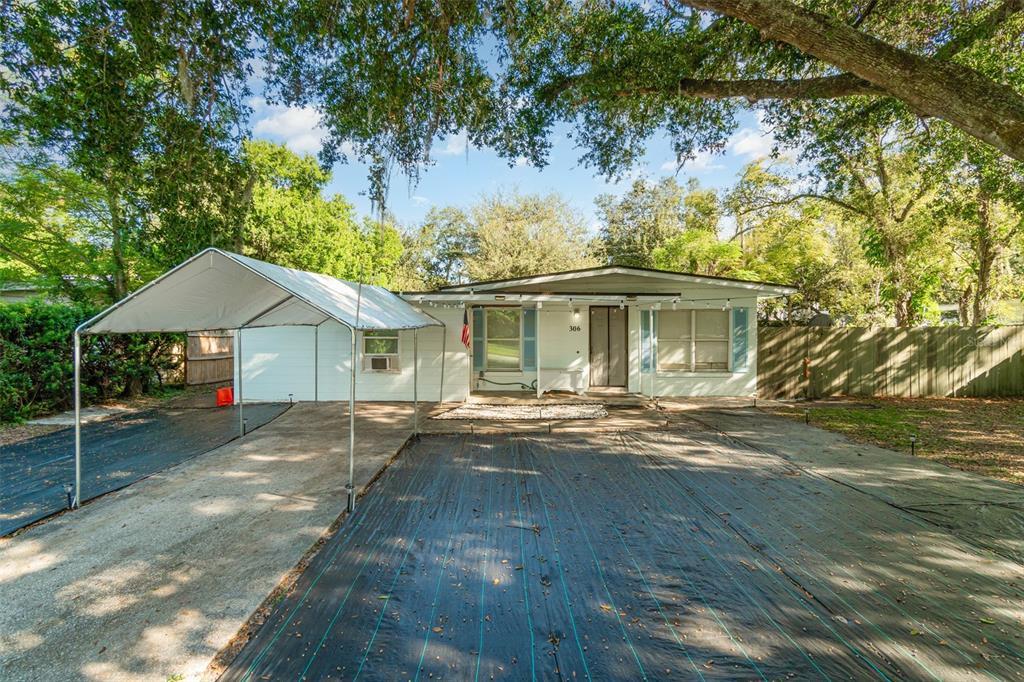 A single-story house with a white exterior, a metal carport, and a landscape fabric yard — 306 FAIRMONT DRIVE, SANFORD, FL