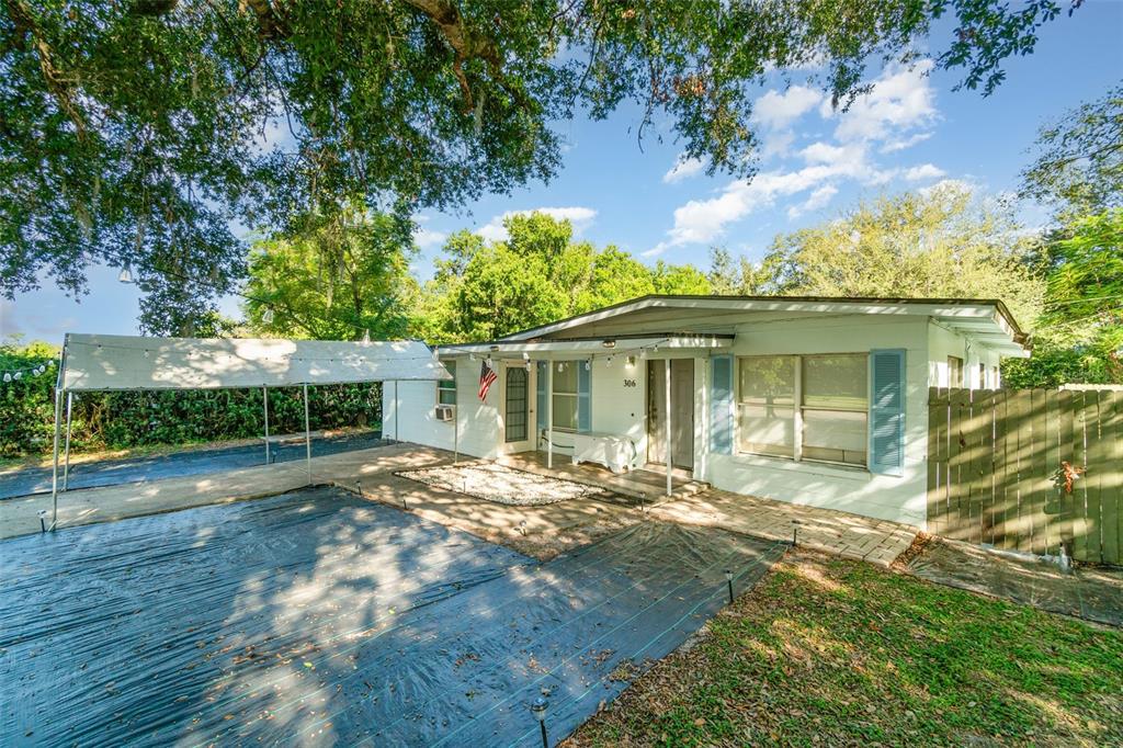 A single-story house with a white exterior, blue shutters, and a metal carport in front — 306 FAIRMONT DRIVE, SANFORD, FL