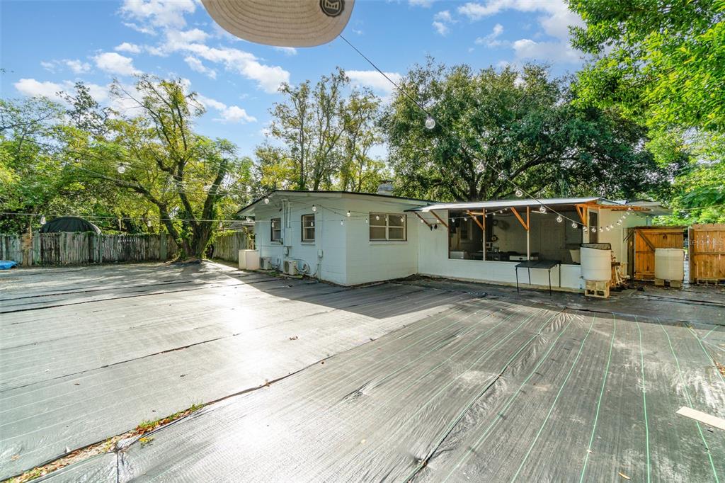 The backyard features a light-colored house with a covered patio and a large landscape fabric — 306 FAIRMONT DRIVE, SANFORD, FL