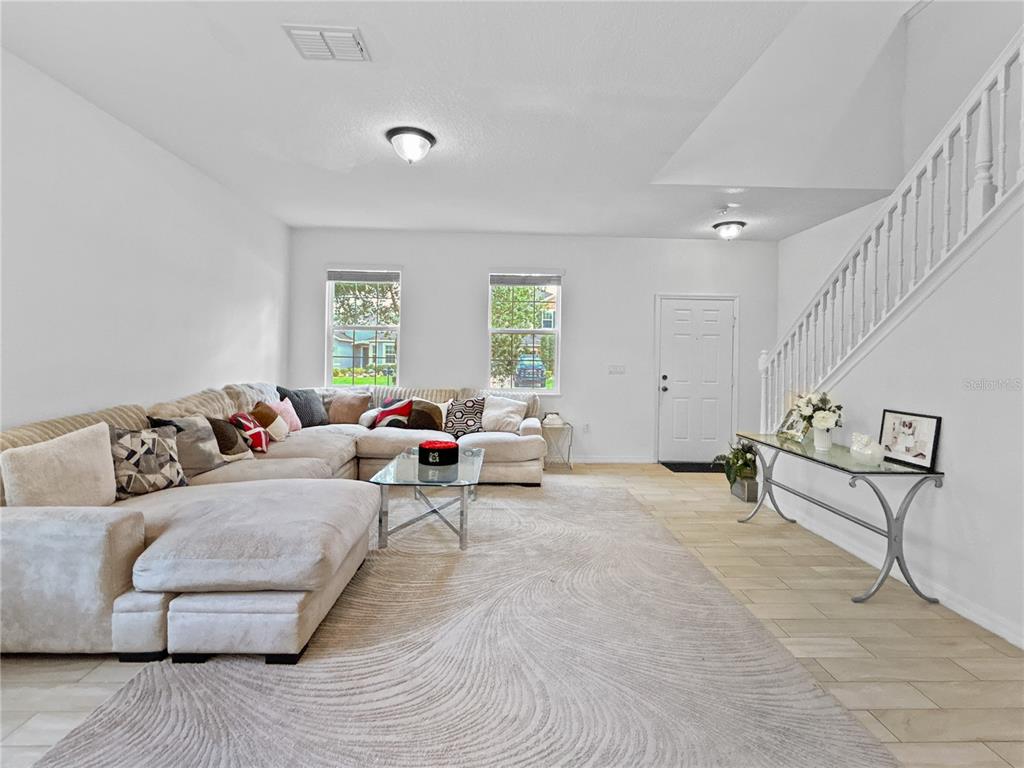 A living room features a large sectional sofa, a glass coffee table, and a staircase — 16100 YELLOWEYED DRIVE, CLERMONT, FL
