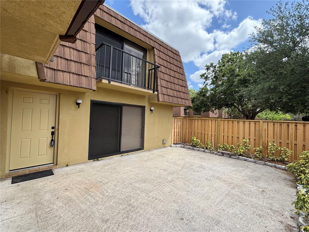 A tan stucco building features a concrete patio, sliding glass doors, and a second-story balcony — 5341 BAMBOO COURT UNIT 418, ORLANDO, FL