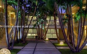 A paved courtyard with palm trees and glowing spherical lights between two apartment buildings at night — 1816 Meridian Ave # 13, Miami Beach FL 33139, MIAMI BEACH, FL