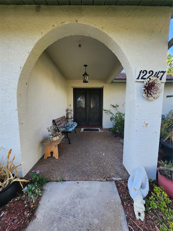 A covered entryway features an arched opening, a textured concrete floor, and a double door — 12247 KATHERWOOD STREET, SPRING HILL, FL