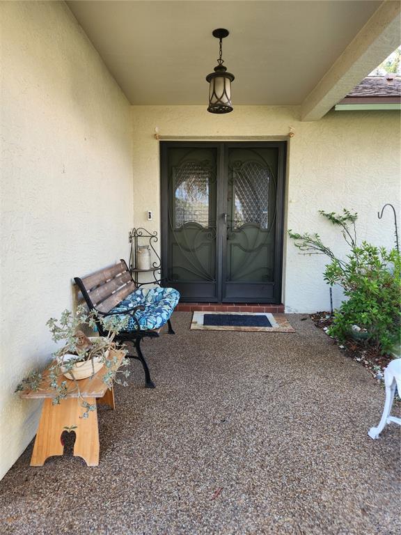 A covered entryway features a double screen door, a bench, and a small wooden table — 12247 KATHERWOOD STREET, SPRING HILL, FL