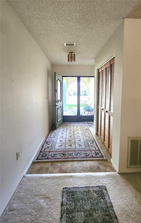 An entryway features a tiled floor, a patterned rug, louvered closet doors, and a front door — 12247 KATHERWOOD STREET, SPRING HILL, FL