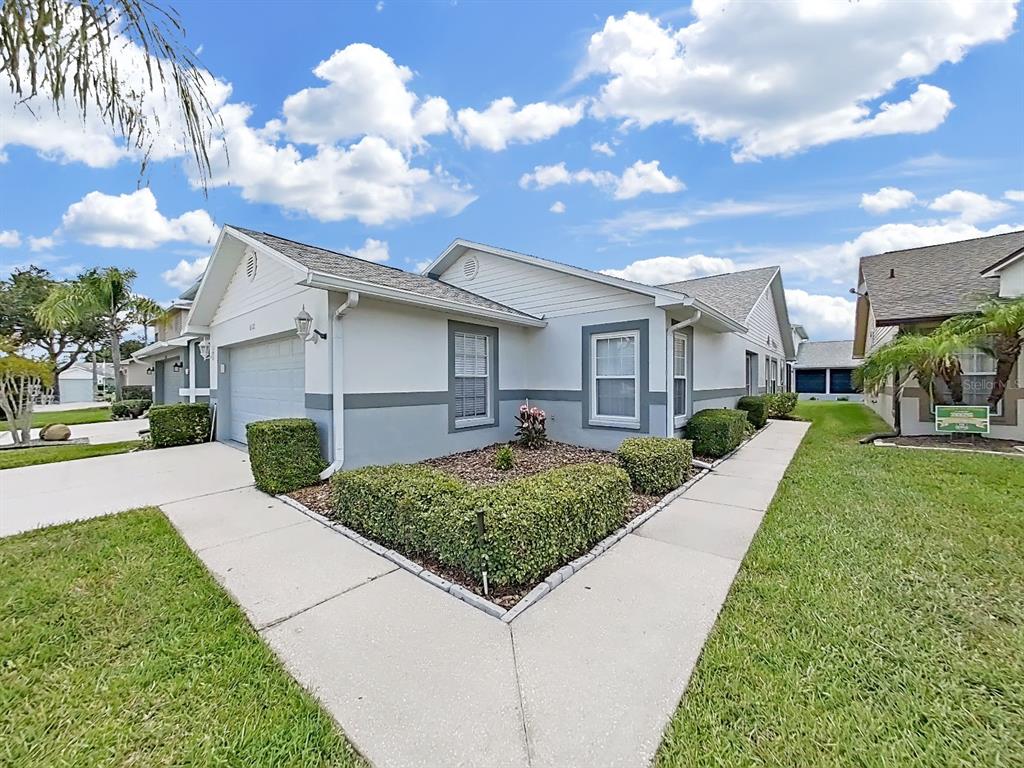 A single-story house with a two-car garage, gray and white exterior, and landscaped front yard — 6122 GENTLE BEN CIRCLE, WESLEY CHAPEL, FL