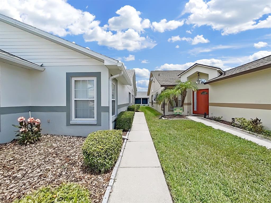 A sidewalk leads between two suburban houses with lawns and a bright red front door — 6122 GENTLE BEN CIRCLE, WESLEY CHAPEL, FL
