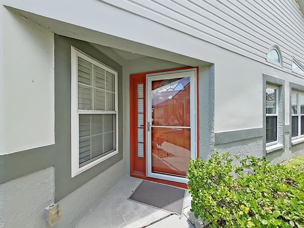 A front entrance features a white storm door with a red frame and a window — 6122 GENTLE BEN CIRCLE, WESLEY CHAPEL, FL