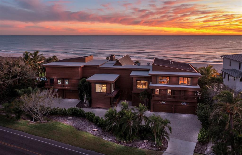An aerial view of a multi-story brown wooden house situated on a beach at sunset — 6685 GULF OF MEXICO DRIVE, LONGBOAT KEY, FL
