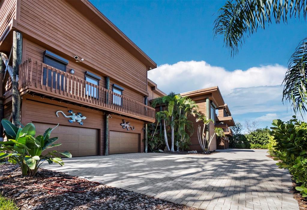 A two-story brown house with a paved driveway, two garage doors, and decorative gecko wall art — 6685 GULF OF MEXICO DRIVE, LONGBOAT KEY, FL