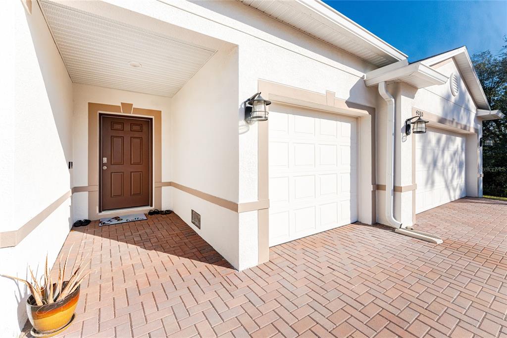 A front exterior view showing a brown door, white garage doors, and a brick driveway — 4080 COLLINGSWOOD BOULEVARD, PORT CHARLOTTE, FL