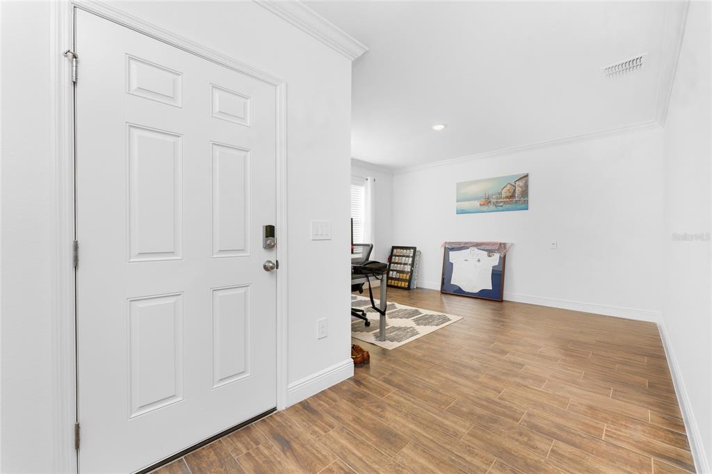 A white front door opens into a room with wood-look tile flooring and white walls — 4080 COLLINGSWOOD BOULEVARD, PORT CHARLOTTE, FL