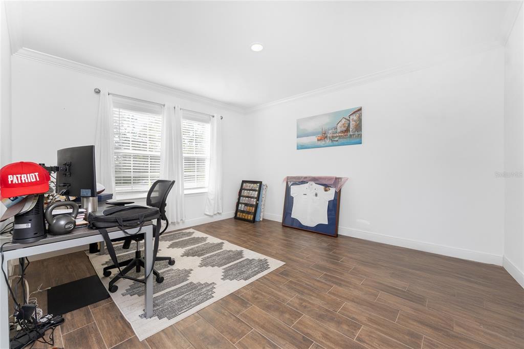 A home office features wood-look tile flooring, a desk, a rug, and wall-mounted decor — 4080 COLLINGSWOOD BOULEVARD, PORT CHARLOTTE, FL