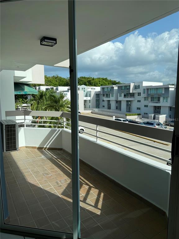 A balcony with tiled flooring overlooks a parking lot and multi-story apartment buildings — 13 Camino Los Baez COND EL BOSQUE, GUAYNABO, PR