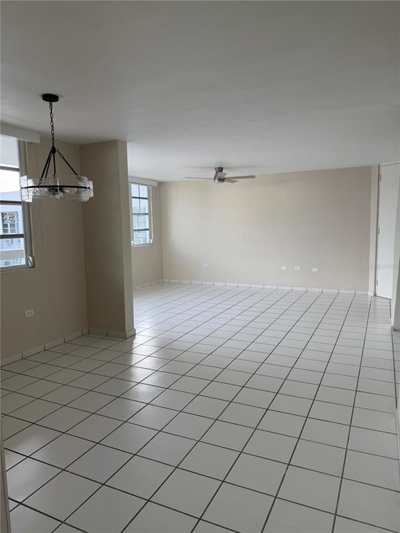 An empty room with white tiled floors, a ceiling fan, and a hanging light fixture — 13 Camino Los Baez COND EL BOSQUE, GUAYNABO, PR