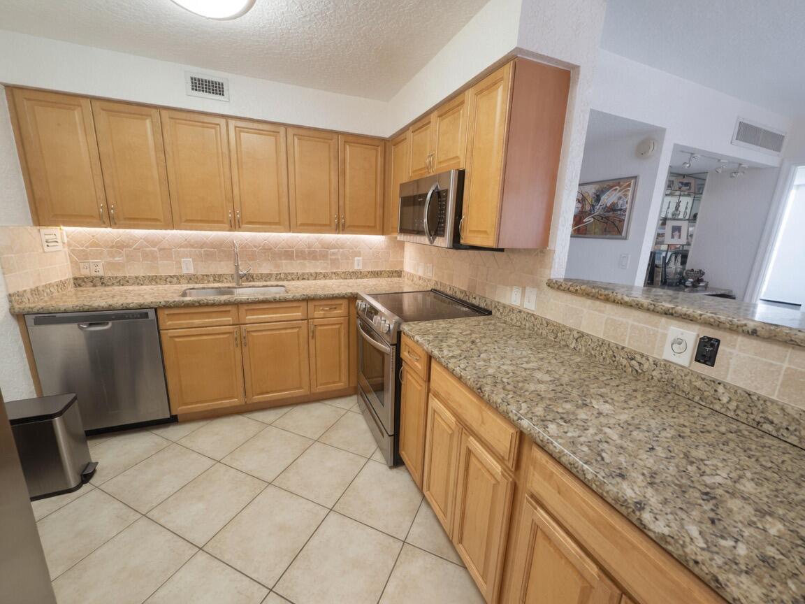 A kitchen with light wood cabinets, granite countertops, stainless steel appliances, and tiled flooring — 1000 Spanish River Road # 4p, Boca Raton FL 33432, BOCA RATON, FL