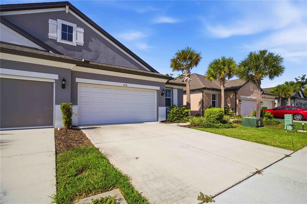 A gray suburban house with a two-car garage and a concrete driveway under a sky — 5918 FIORE DRIVE, BRADENTON, FL