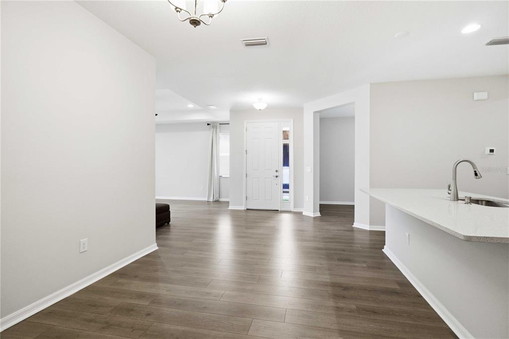 An open-concept living area features light gray walls, wood-look flooring, and a kitchen island — 5918 FIORE DRIVE, BRADENTON, FL