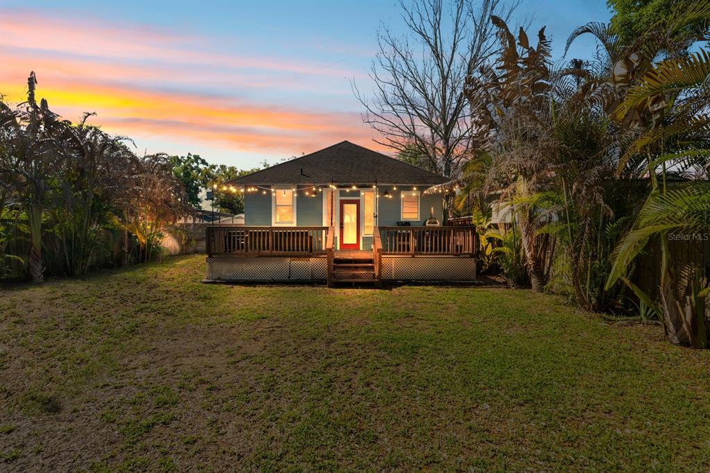 A backyard view of a single-story house with a wooden deck and string lights — 200 E FERN STREET, TAMPA, FL