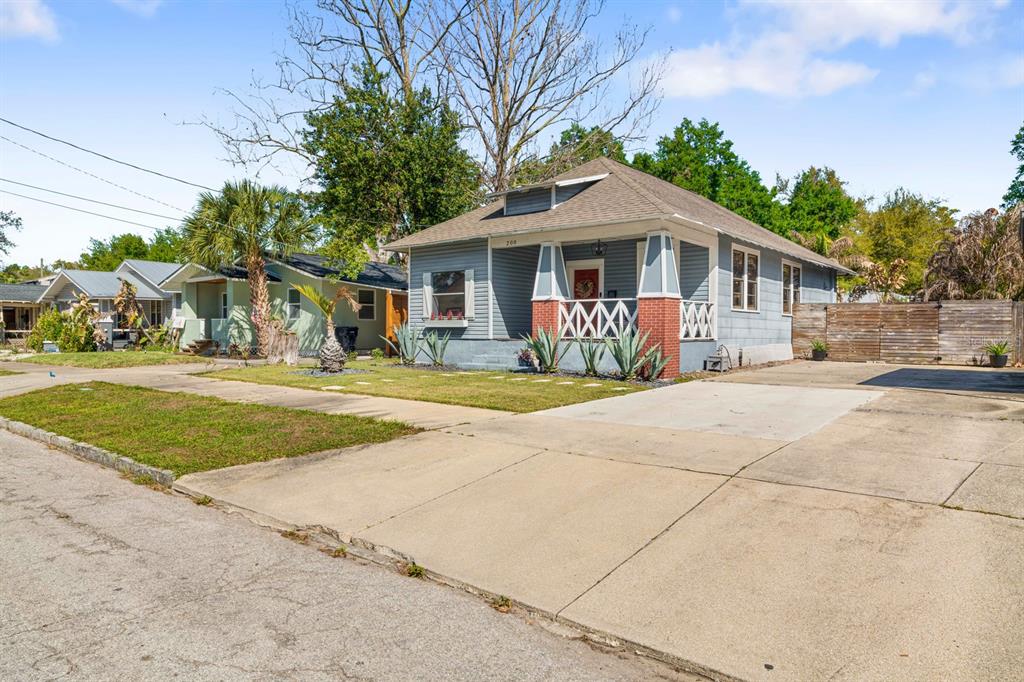 A light blue bungalow with a front porch and a concrete driveway sits on a street — 200 E FERN STREET, TAMPA, FL