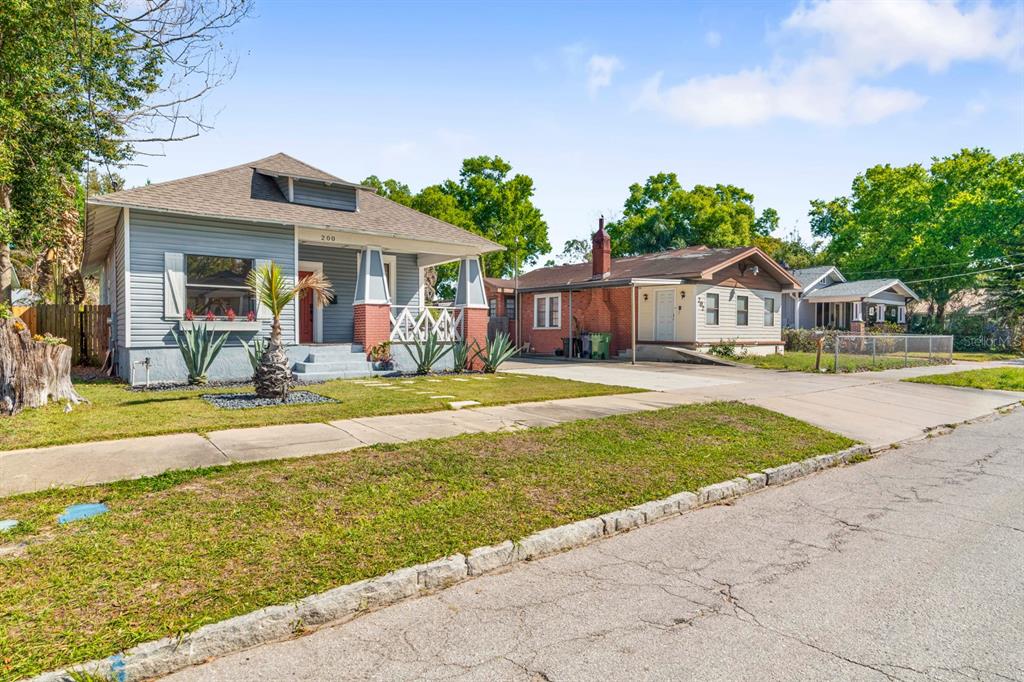 A gray bungalow with a front porch sits next to a brick-accented house — 200 E FERN STREET, TAMPA, FL